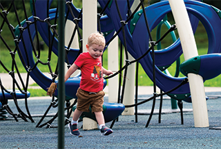 Little boy in a red shirt playing on blue slide