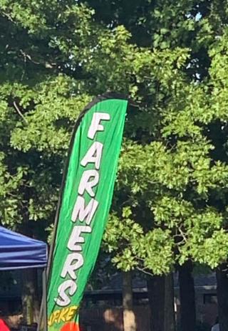 green flag in park that reads Farmers Market